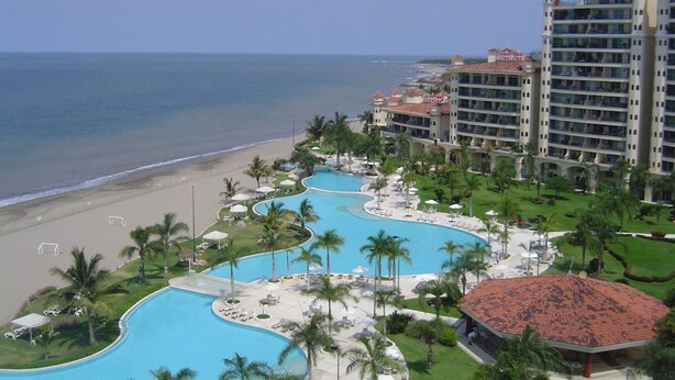 A resort with a large pool area, beachfront, and multiple hotel buildings.