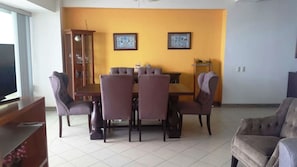 A dining area with a table and chairs, a cabinet, and two framed pictures on the wall.