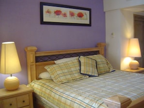 A bedroom with a bed, two bedside lamps, a nightstand, a dresser, and a framed picture on the wall. - Unlimited Luxury SANMILLAN'S Condo (Puerto Vallarta)