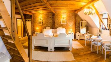 A bedroom with a wooden ceiling, a white bed, a nightstand, a chair, and a small table with a vase of flowers.