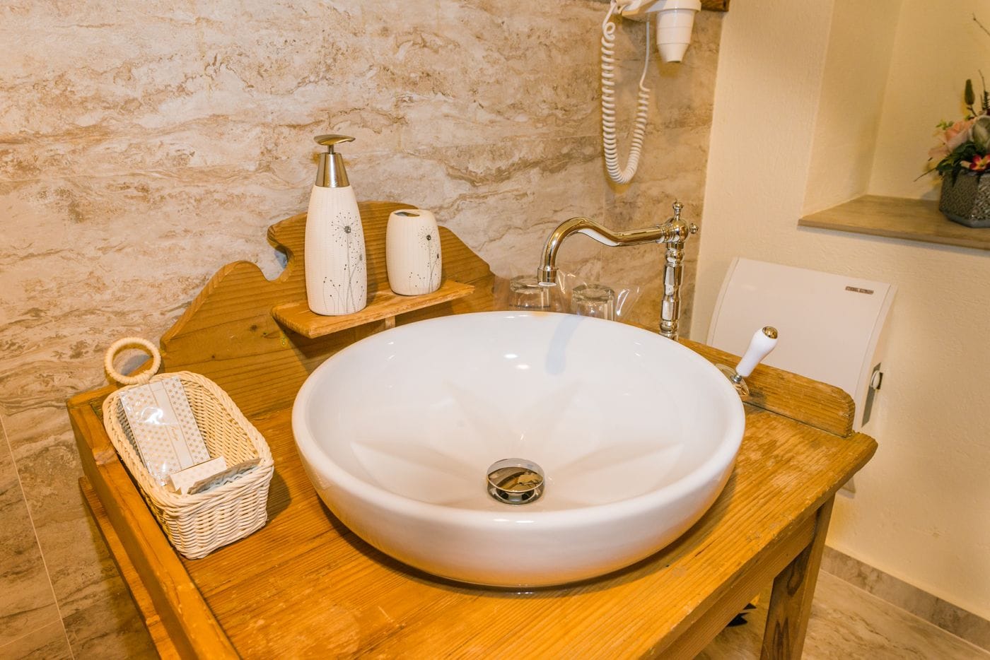 A bathroom with a large white sink, wooden vanity, and a towel rack.