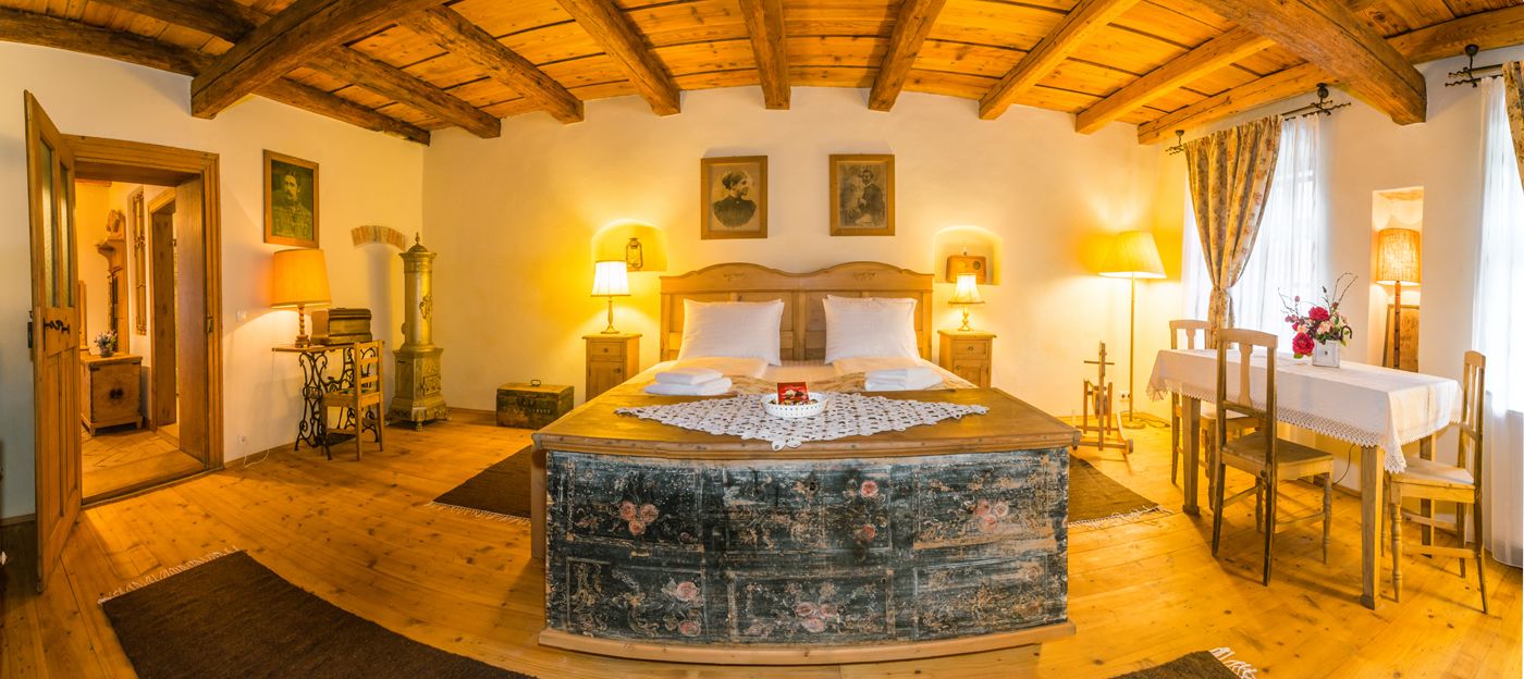 Une chambre à coucher avec un grand lit, des poutres apparentes en bois au plafond et une esthétique rustique.