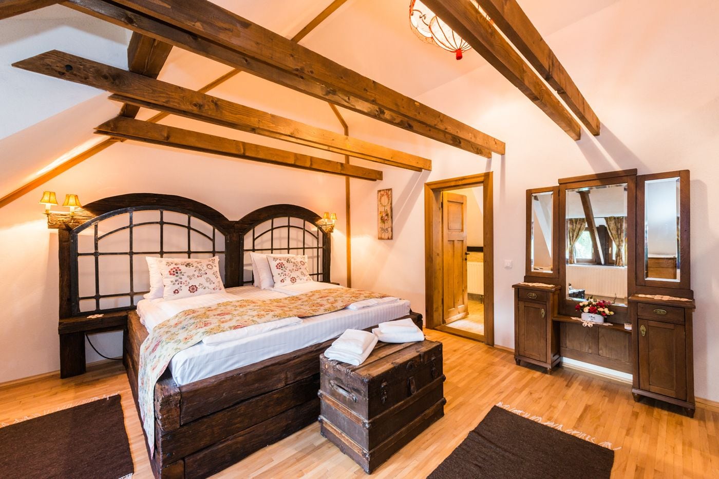 Une chambre à coucher avec un lit en bois, une commode, un miroir et un plafond en bois.