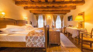 A cozy room with two beds, a wooden table, and a TV.