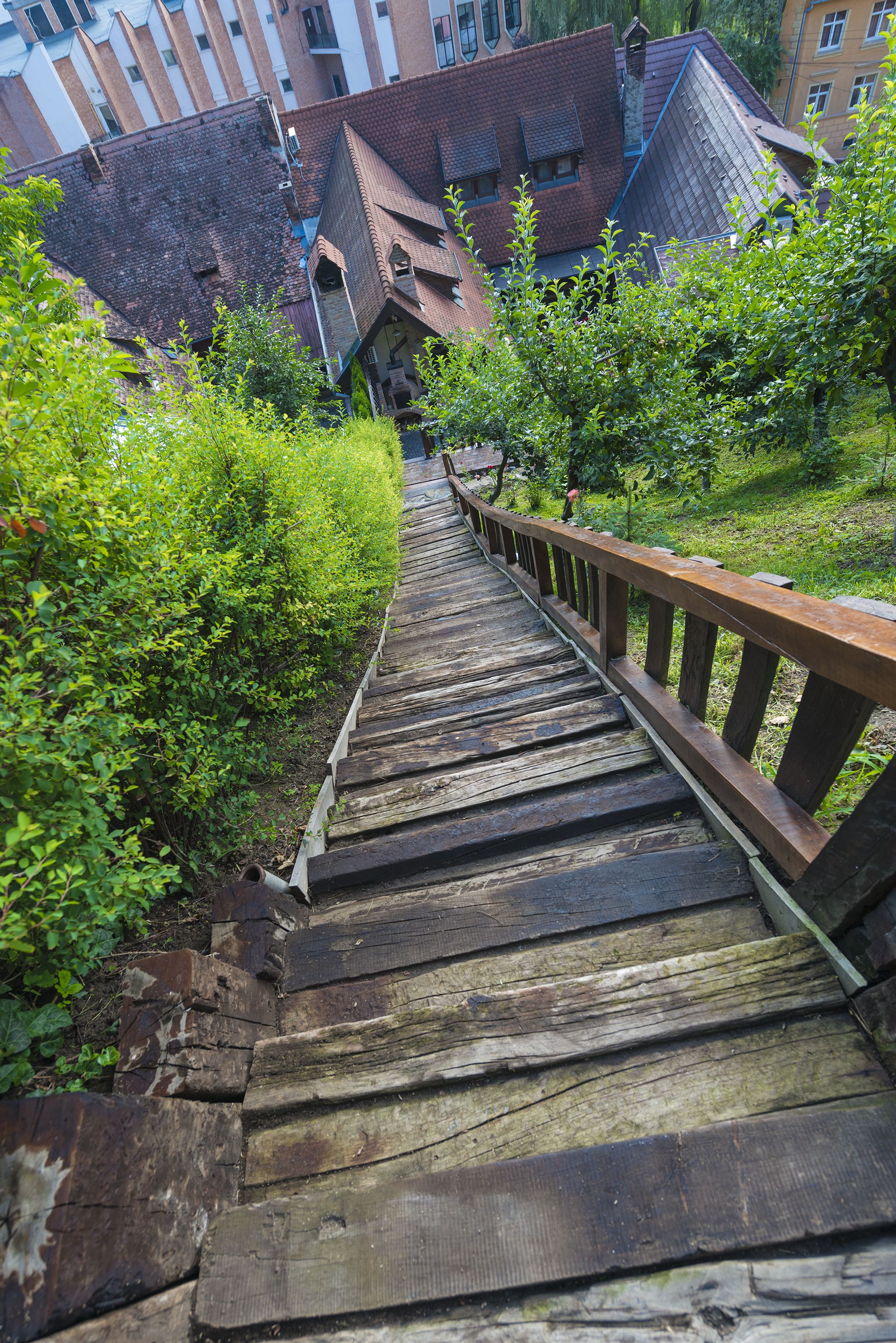 Un escalier en bois mène à un immeuble dont la façade est en briques et qui possède de nombreuses fenêtres.