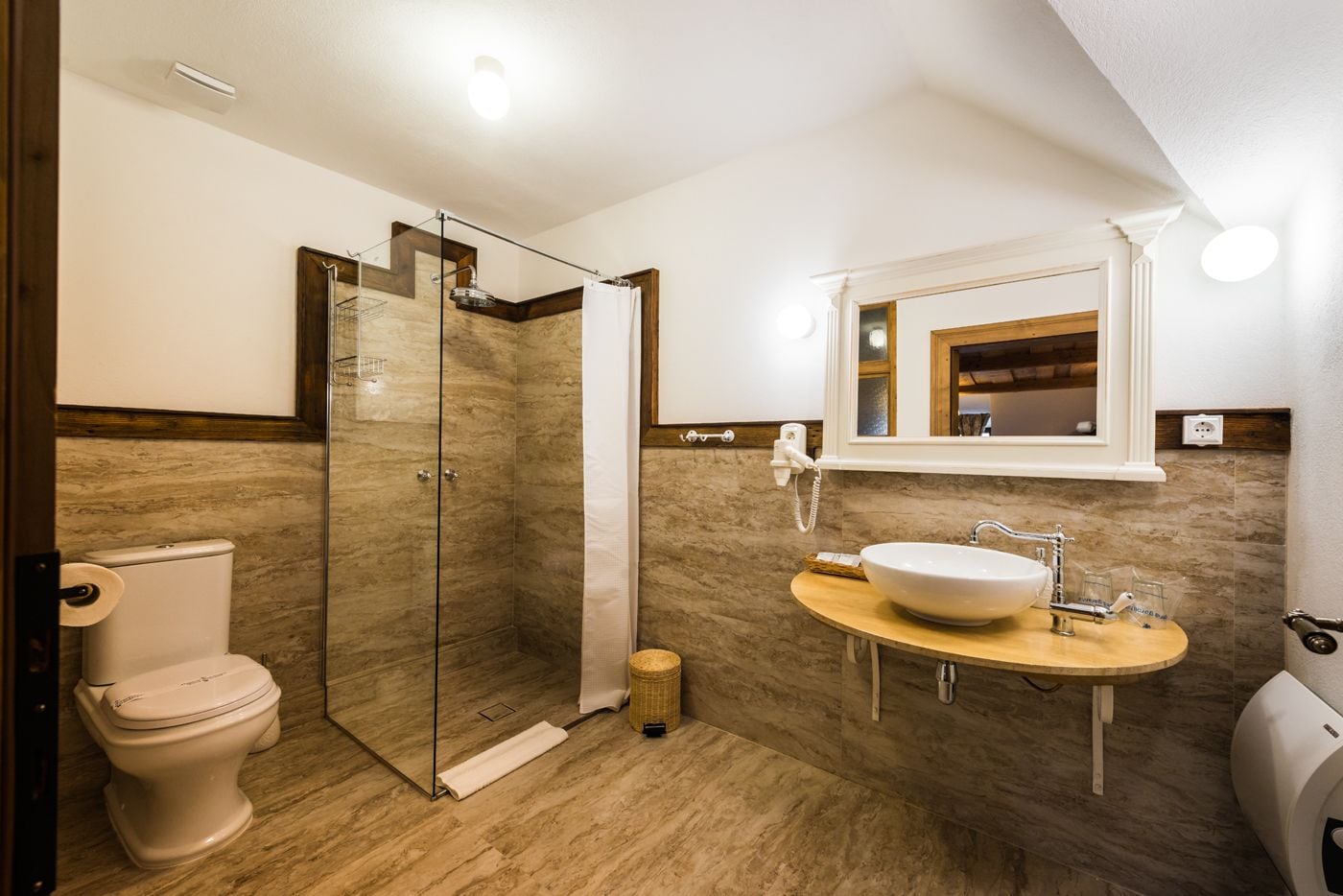 A modern bathroom with a glass-enclosed shower, a toilet, and a sink with a mirror above it.