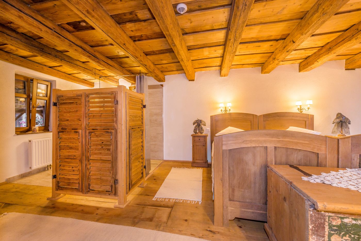 Een houten kamer met een bed, een houten kledingkast en een radiator.