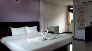 A hotel room with a neatly made bed, a small refrigerator, and a door with a floral design. - Nan Green View Hotel (Nan)
