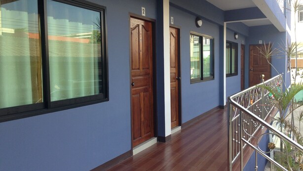 A corridor with wooden doors and windows, a metal railing, and a tiled floor. - Nan Green View Hotel (Nan)