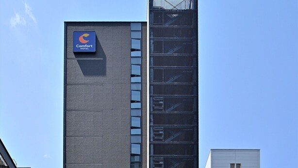 Um edifício alto e moderno com uma fachada onde se destaca a placa Comfort Hotel.