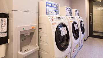 A row of white, modern laundry machines with control panels and safety instructions.