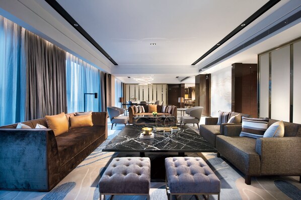 A modern hotel lobby with a central seating area, a dining table, and a bar.