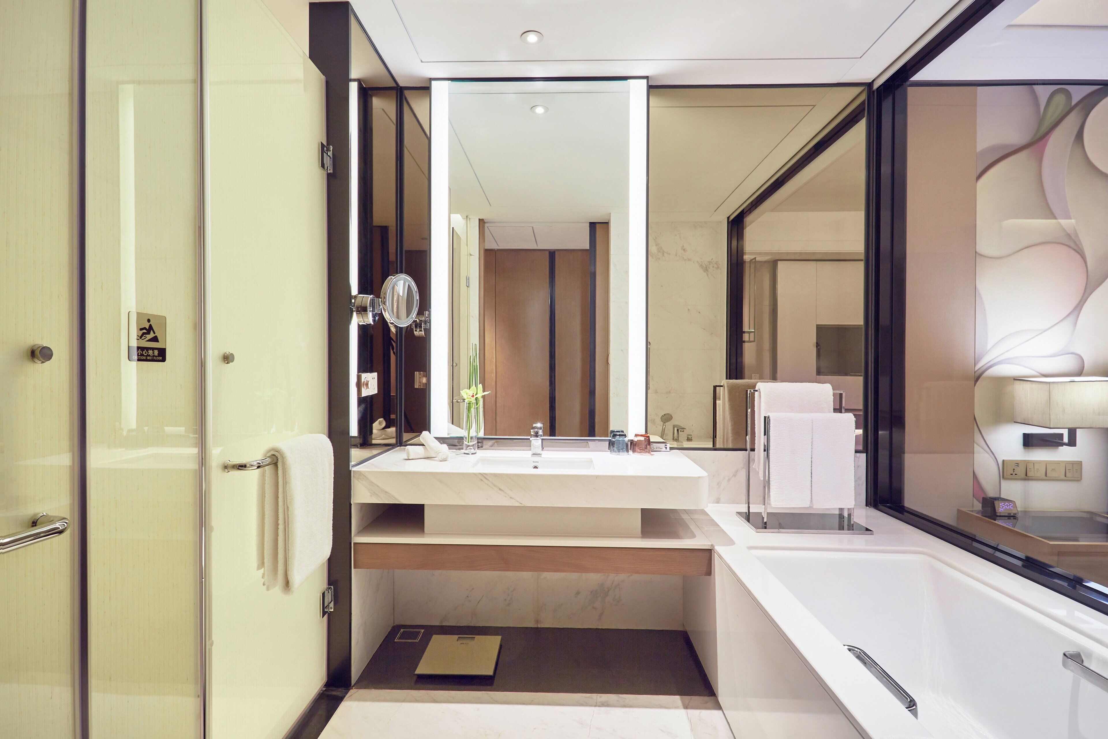 A modern bathroom with a large mirror, a sink, and a towel rack.