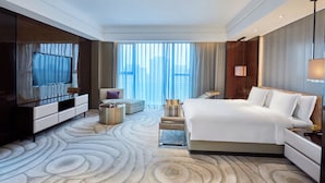 Hotelkamer met een groot bed, een televisie, een zithoek en uitzicht op de stad.