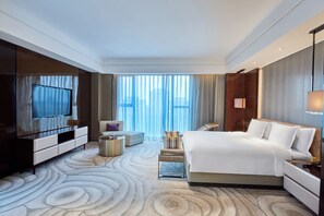 Une chambre d’hôtel avec un grand lit, une télévision, un coin salon et une vue sur la ville.