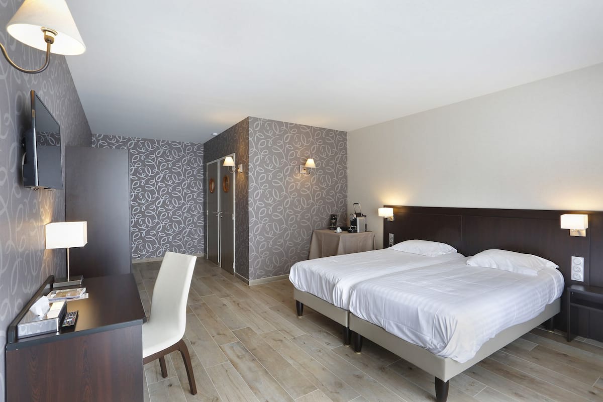 Una habitación de hotel con cama, mesitas de noche, un escritorio con silla y televisor.