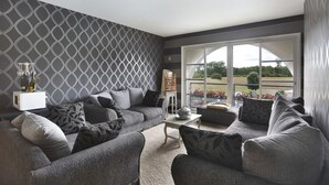 Un salon moderne avec des canapés gris, une table basse et un papier peint à motifs.