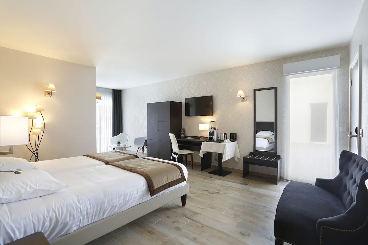 Habitación de hotel con cama, escritorio, silla y un espejo grande.