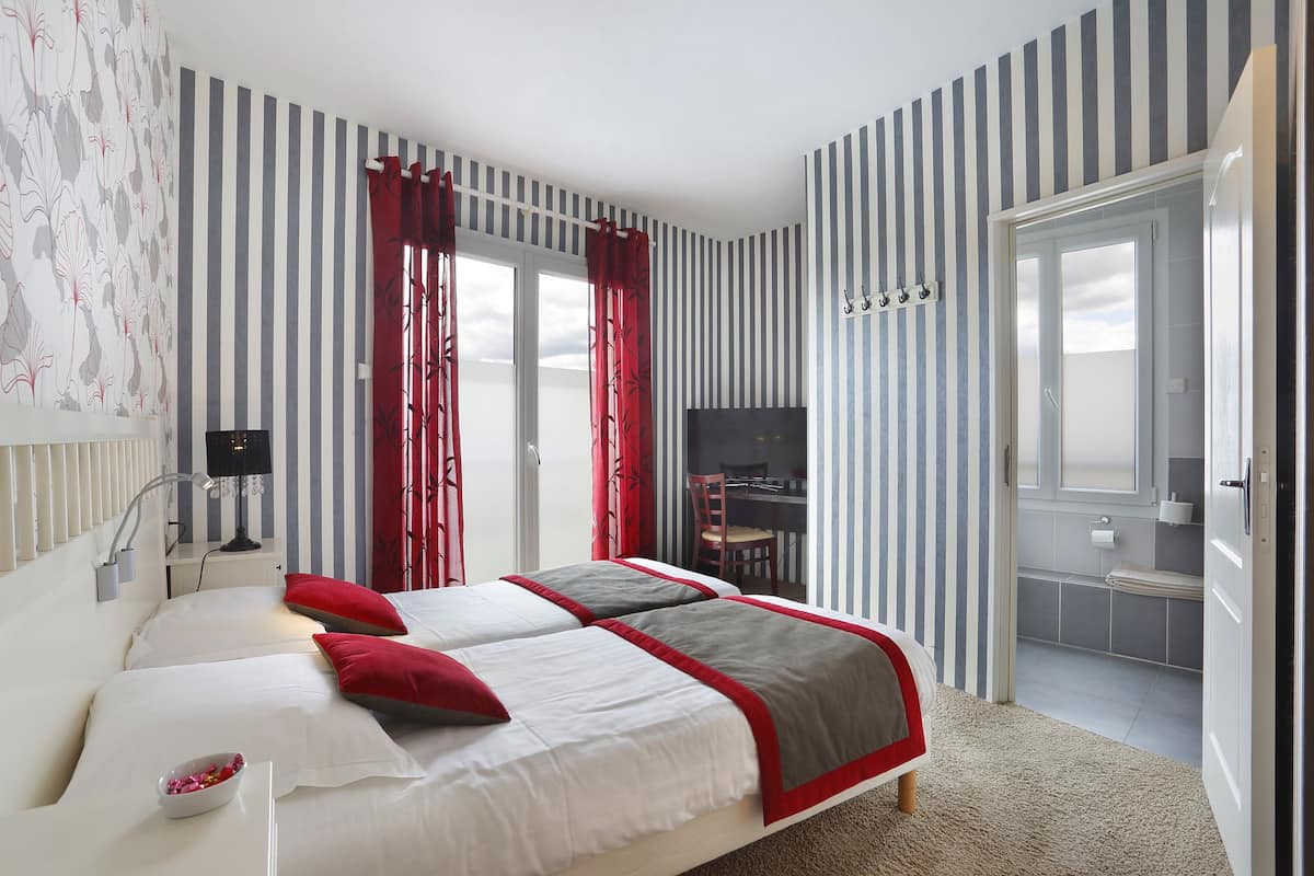 Habitación de hotel con cama doble, televisión, escritorio con silla y balcón con vistas.