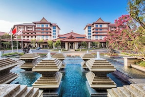 A hotel with a traditional architectural style, featuring a central courtyard with a water feature and tiered steps.