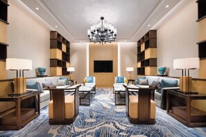 A hotel lobby with a central seating area, a chandelier, and built-in bookshelves.