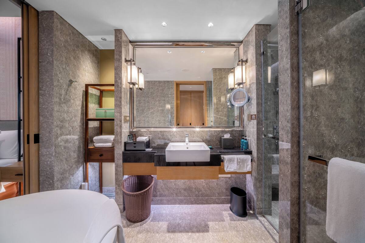 Une salle de bain moderne avec un grand miroir, un lavabo et une douche.