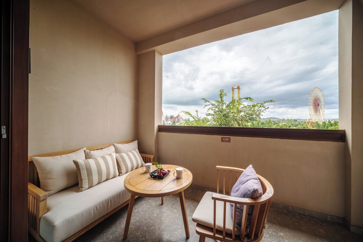 Ein Balkon mit einer Couch, einem kleinen Tisch mit einer Fruchtschale und zwei Tassen sowie einem Stuhl mit einem Handtuch.