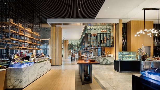 Un intérieur moderne avec un espace salon central, un plancher en bois et des vitrines.