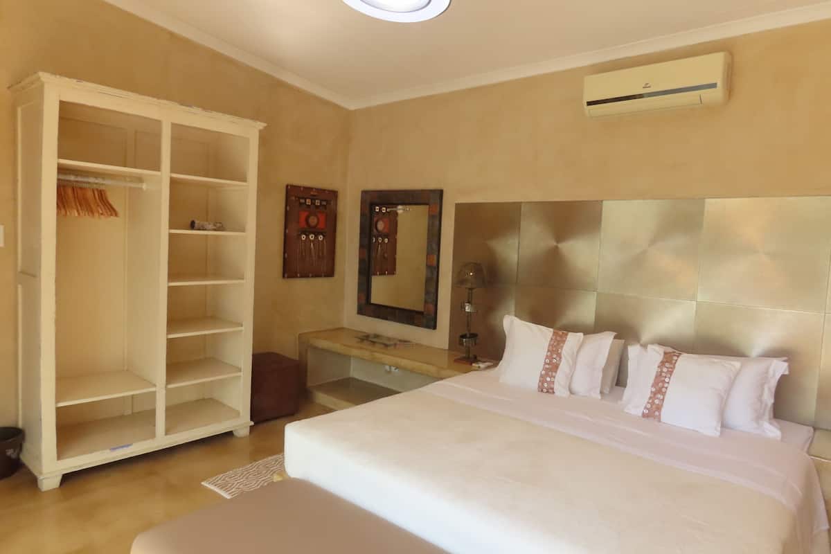 Une chambre d’hôtel avec un grand lit, une armoire, une coiffeuse avec un miroir et un appareil de climatisation fixé au mur.