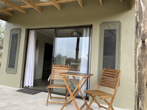 Una mesa de madera y dos sillas frente a un edificio con puerta corrediza de vidrio.