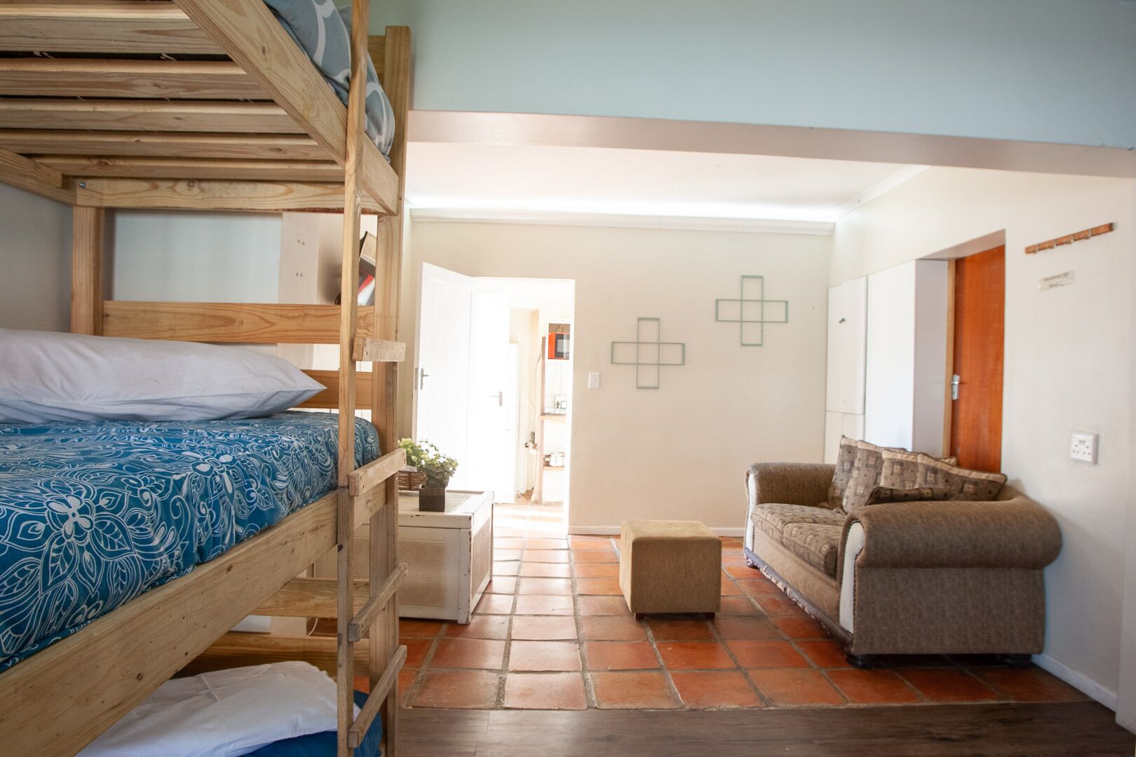 Una habitación con literas, un sofá y una pequeña mesa con una planta.