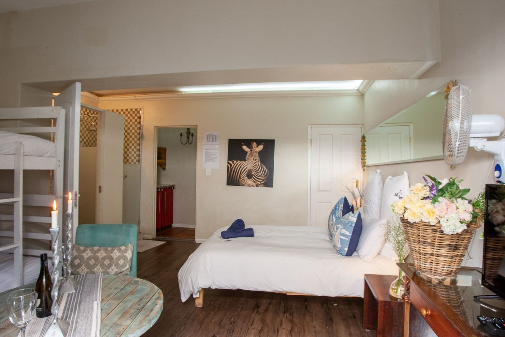 A room with a bed, a dining table with chairs, a kitchen area, and a bathroom.