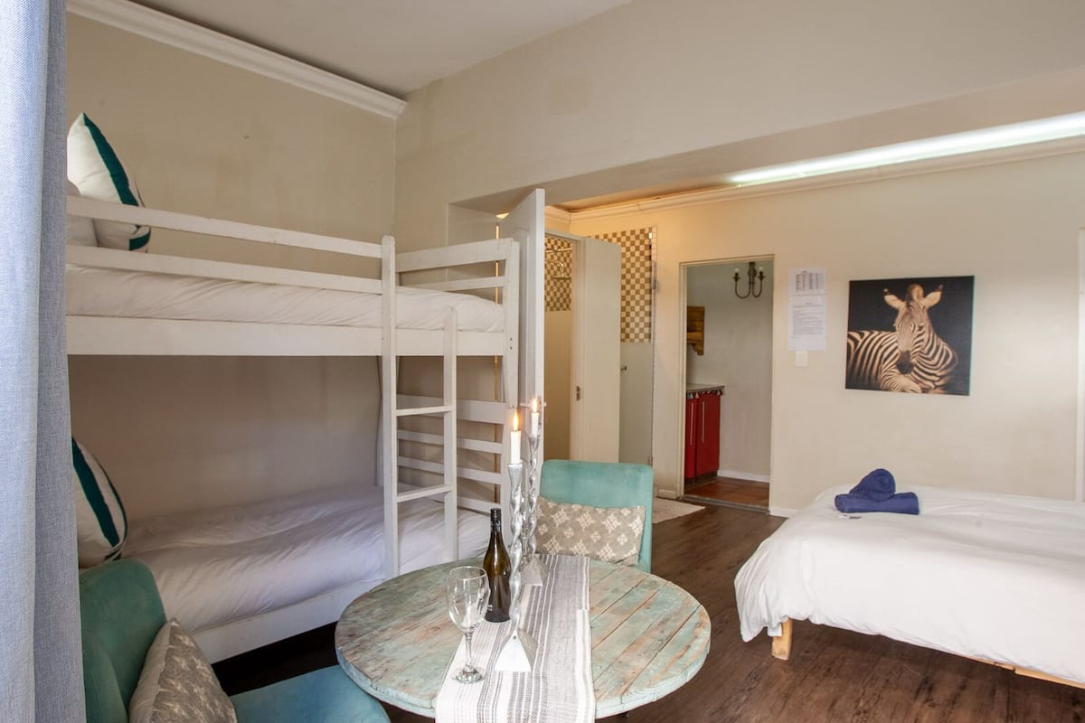 Ein Zimmer mit Etagenbetten, einem runden Tisch mit Kerze und einem Zebra-Gemälde an der Wand.