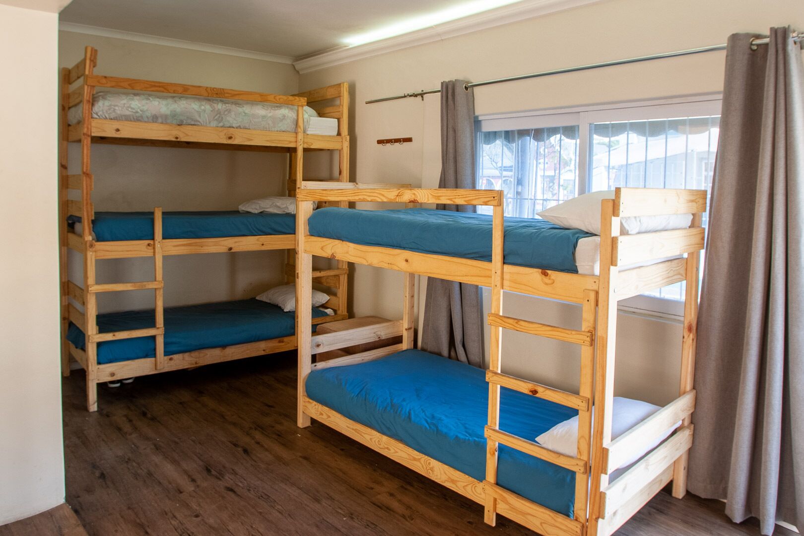 A bunk bed room with three wooden bunk beds, each with blue bedding.