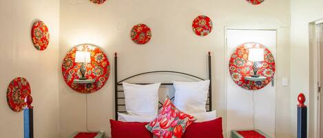 A bedroom with a bed, two nightstands, and multiple wall-mounted lamps.