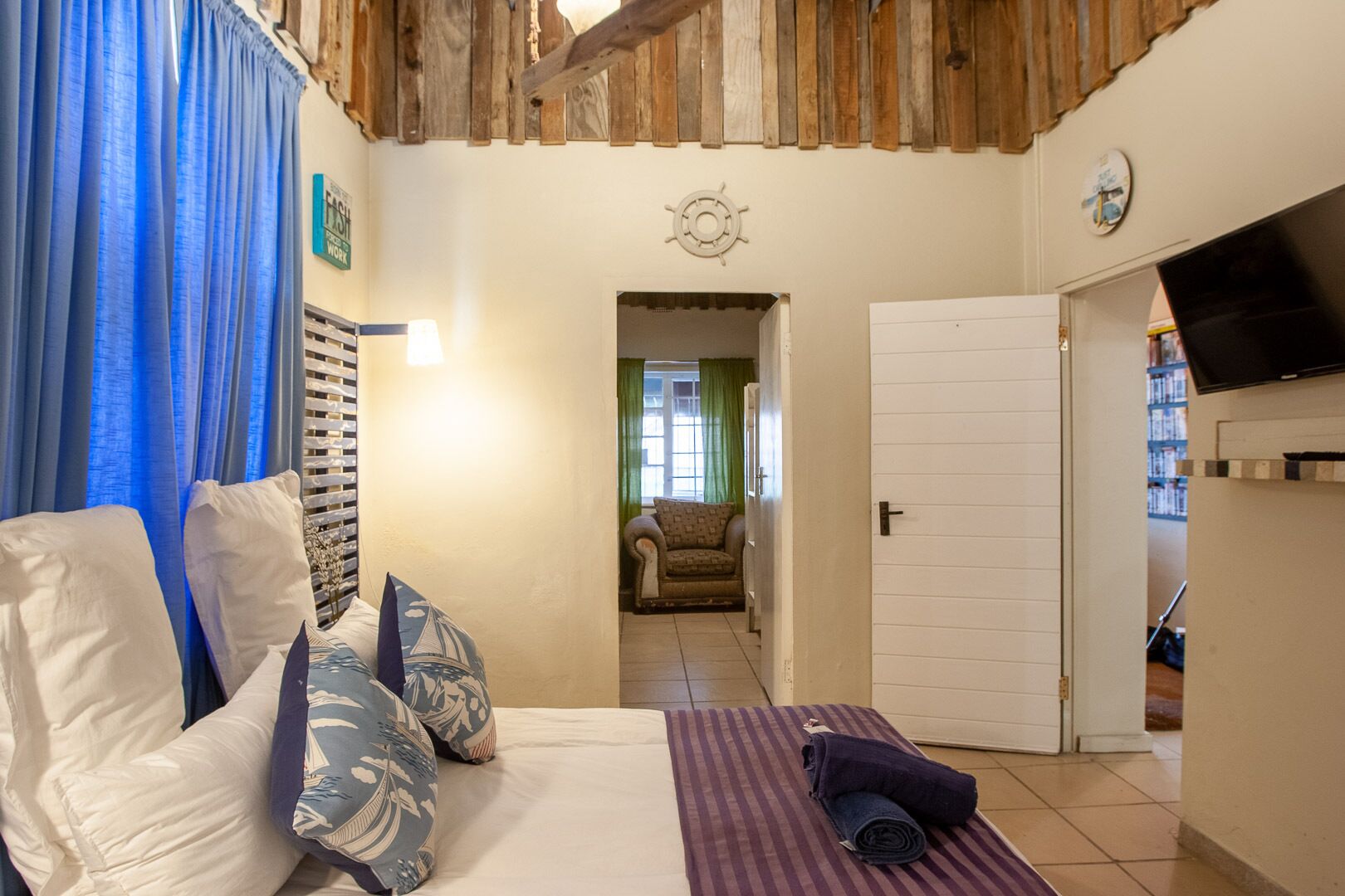 A cozy room with a bed, a TV, and a door leading to another room.