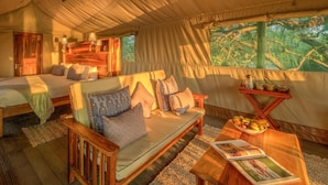 Een accommodatie met tent, twee bedden, een slaapbank en een eethoek.