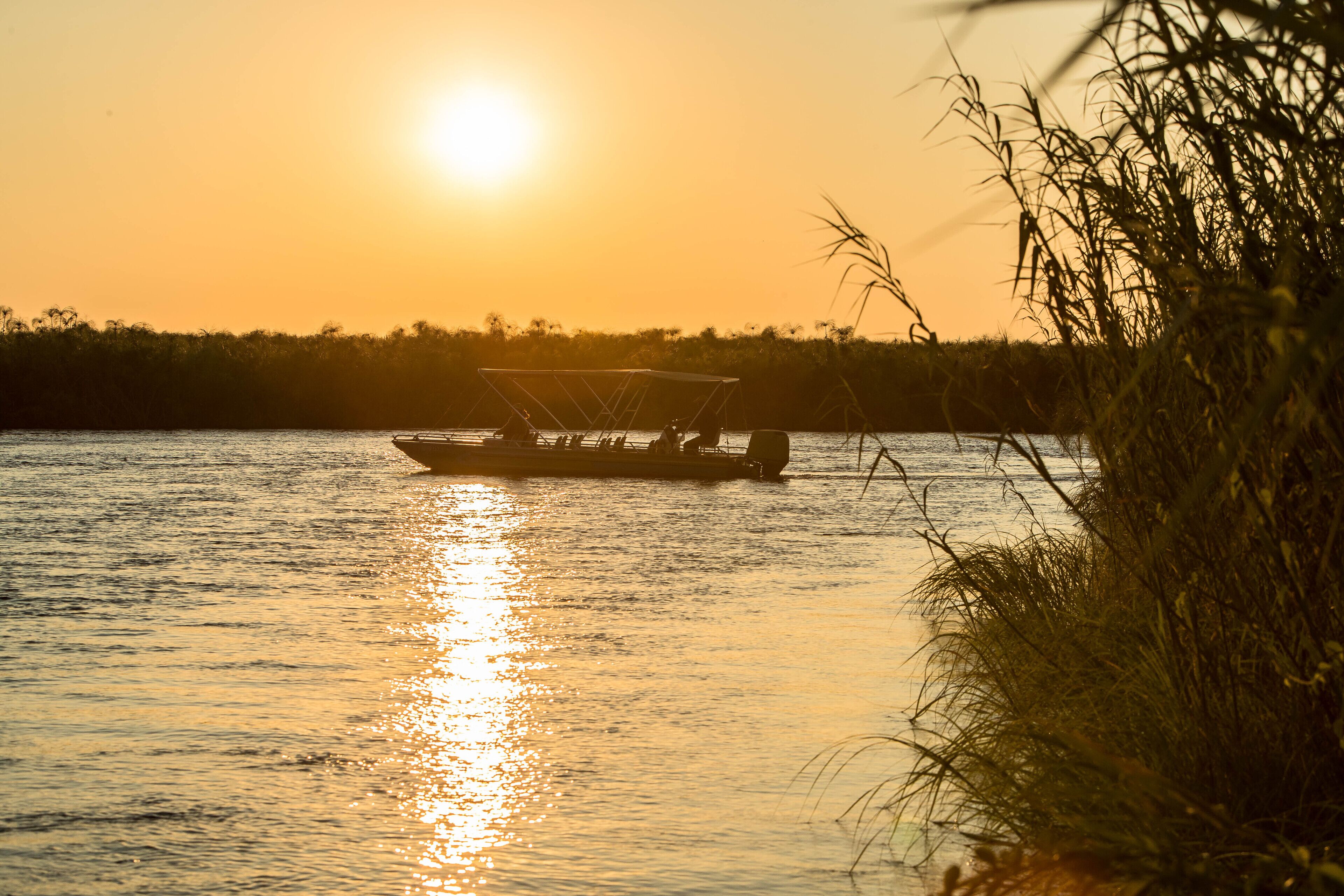 Un bote en aguas tranquilas con un atardecer de fondo.