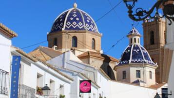 A street with white buildings, a blue dome, and a clock.