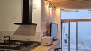 A modern kitchen with a wooden ceiling, a built-in microwave, and a large sliding glass door leading to a balcony.