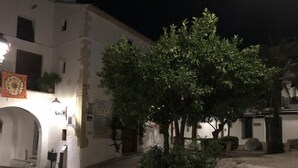 A courtyard with a white building, stone steps, and a tree.