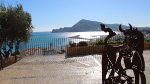 A sculpture of bulls in a public square with a view of the sea and mountains in the background.
