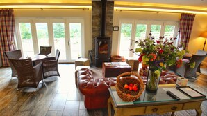 Una sala de estar acogedora con chimenea, muebles de mimbre y una mesa de centro de cristal con una cesta de frutas.