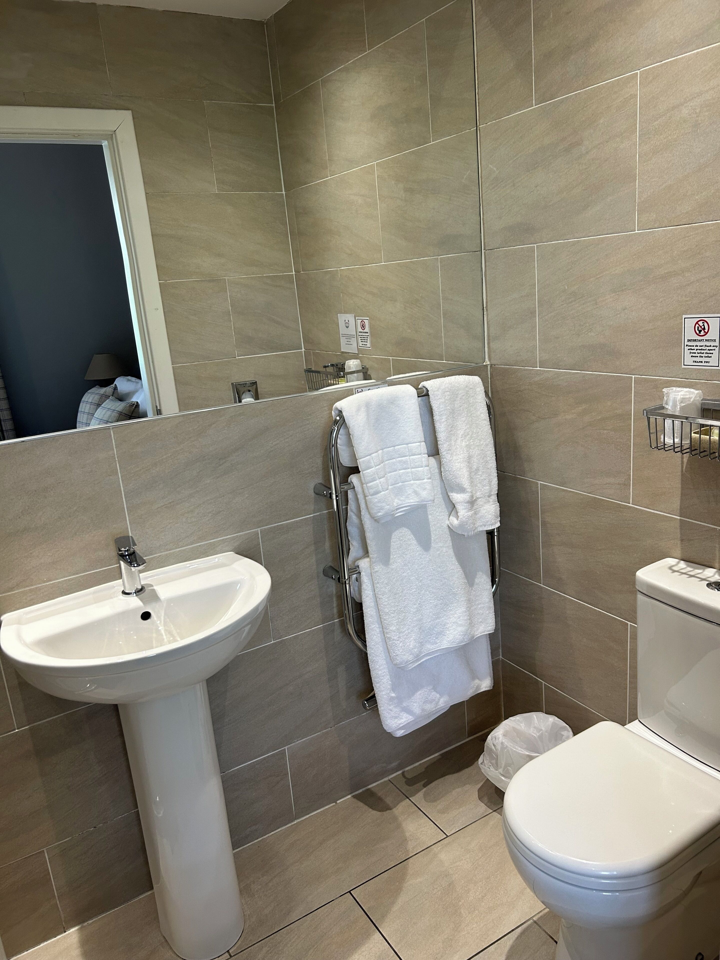A bathroom with a sink, toilet, and towel rack.