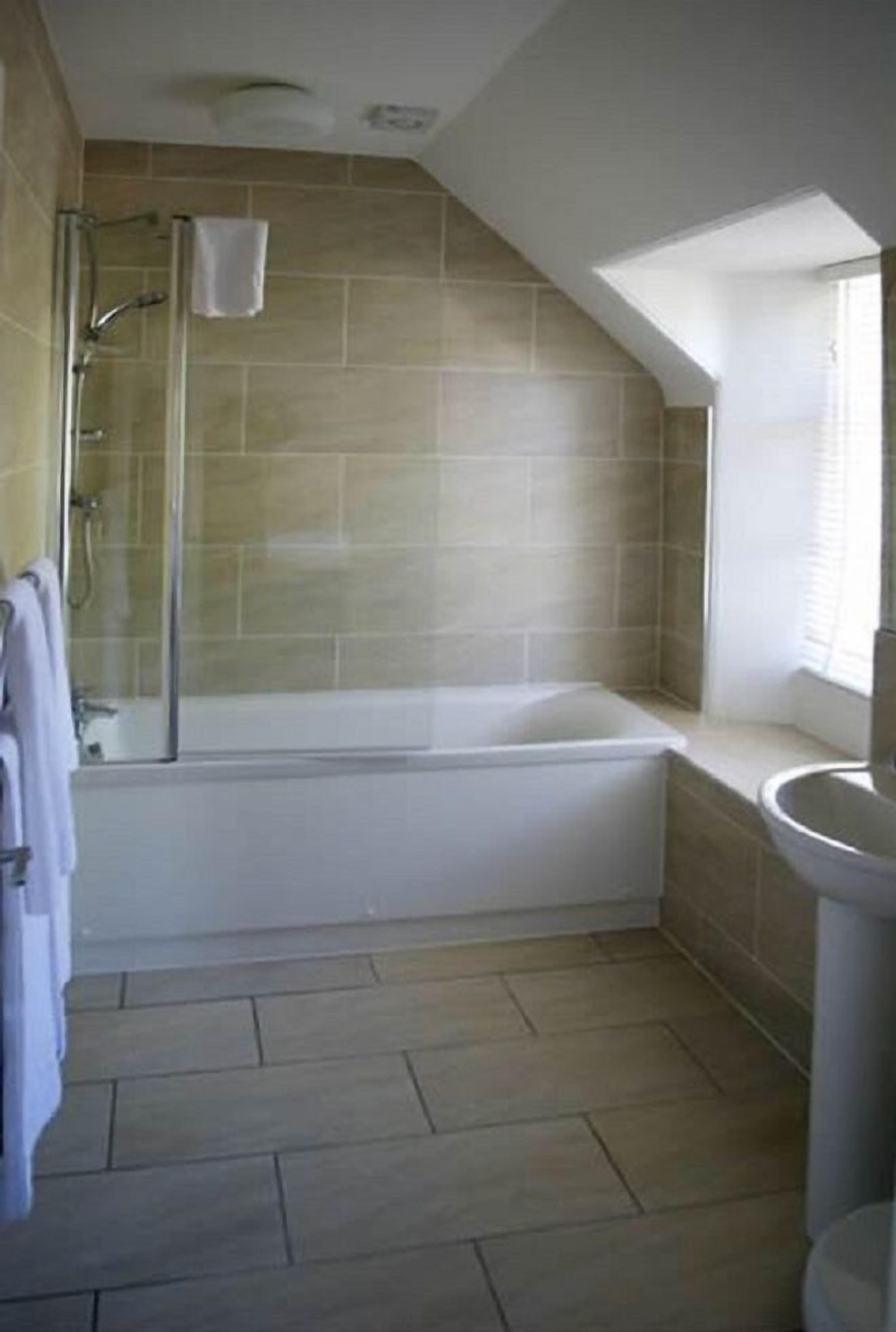 A bathroom with a bathtub, shower, and sink.