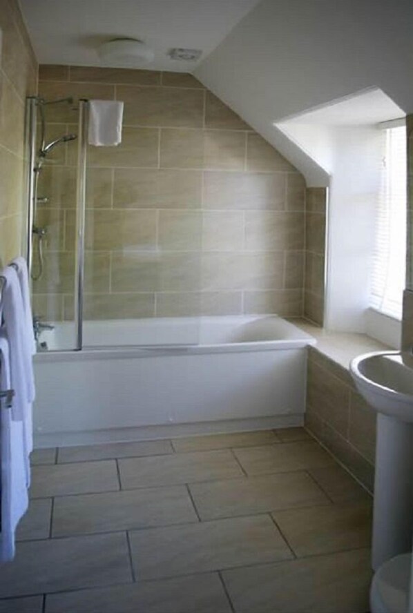 Une salle de bain avec une baignoire, une douche et un lavabo.