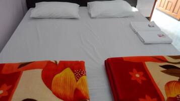 Un lit avec des draps blancs, deux oreillers et une serviette pliée sur le côté.