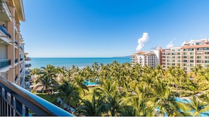 Un resort con zona de piscina rodeada de palmeras, con vistas a una playa y al océano.