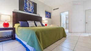 Hotellihuone, jossa on suuri sänky, kaksi yöpöytää valaisimineen, sängynpääty ja taideteoksia seinillä.