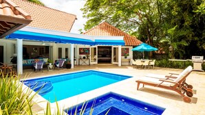 A swimming pool with a tiled deck, lounge chairs, and a covered patio area with outdoor furniture. - Unlimited Luxury Laureanne's Villa (La Romana)